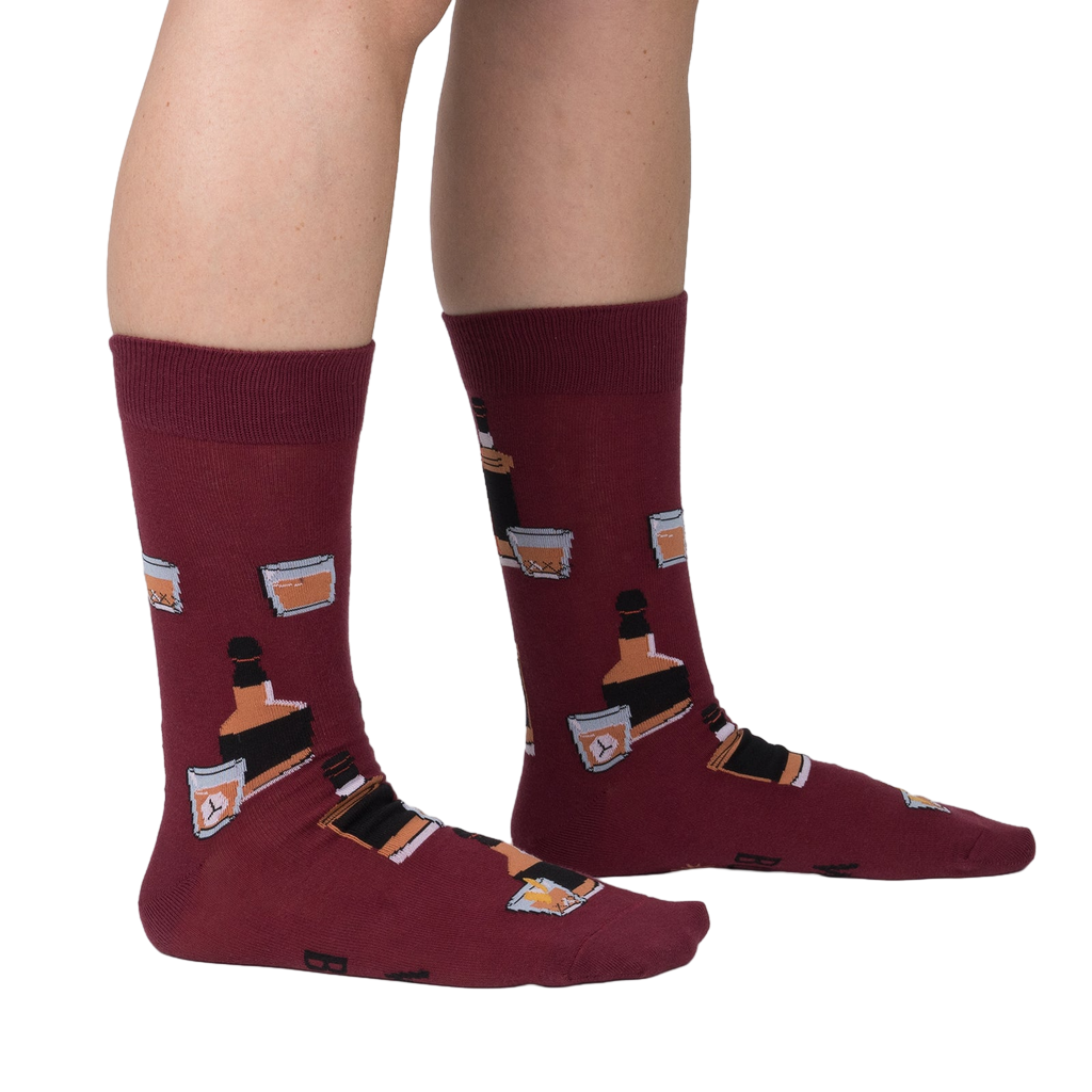 Lifestyle shot showing the Whiskey Business socks on a person's legs.  Burgundy socks with whiskey bottle and glass design.