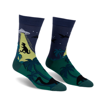 Pair of crew socks with a dark blue upper and green lower. Design shows a UFO abducting a T-Rex, with palm trees.