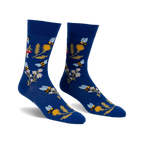 Pair of blue crew socks with whimsical bee, flower, and mushroom design.  Features yellow, white, and red accents.