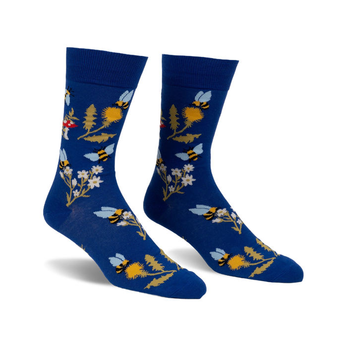 Pair of blue crew socks with whimsical bee, flower, and mushroom design.  Features yellow, white, and red accents.