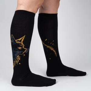 Lifestyle shot showing the Night Cat knee-high socks on a person's legs, showcasing the fit and design.
