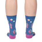 Back view of model wearing a pair of blue crew socks with seahorse and bubble design.