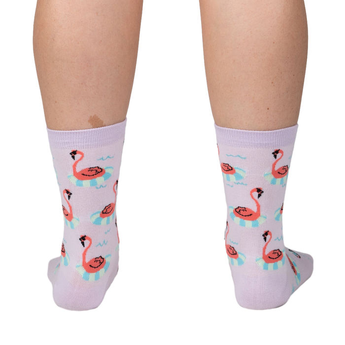 Back view of a person wearing lavender crew socks featuring a repeating pattern of flamingos on inflatable rings.
