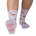 Close-up of a person's feet showcasing the 'Party Like A Flock Star' text on the sole of a lavender crew sock, accompanied by a flamingo design.