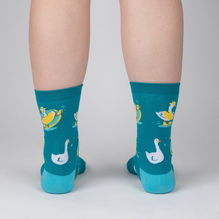 Back view of model wearing teal Silly Goose socks. The socks feature a fun pattern of geese.