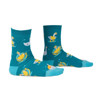 Pair of teal crew socks with a whimsical pattern of geese floating on inner tubes and swimming. Yellow and white geese on teal background.