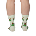 Back view of legs wearing pale crew socks featuring a pattern of green pixel frogs in brown cowboy hats and yellow stars.