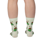 Back view of legs wearing pale crew socks featuring a pattern of green pixel frogs in brown cowboy hats and yellow stars.