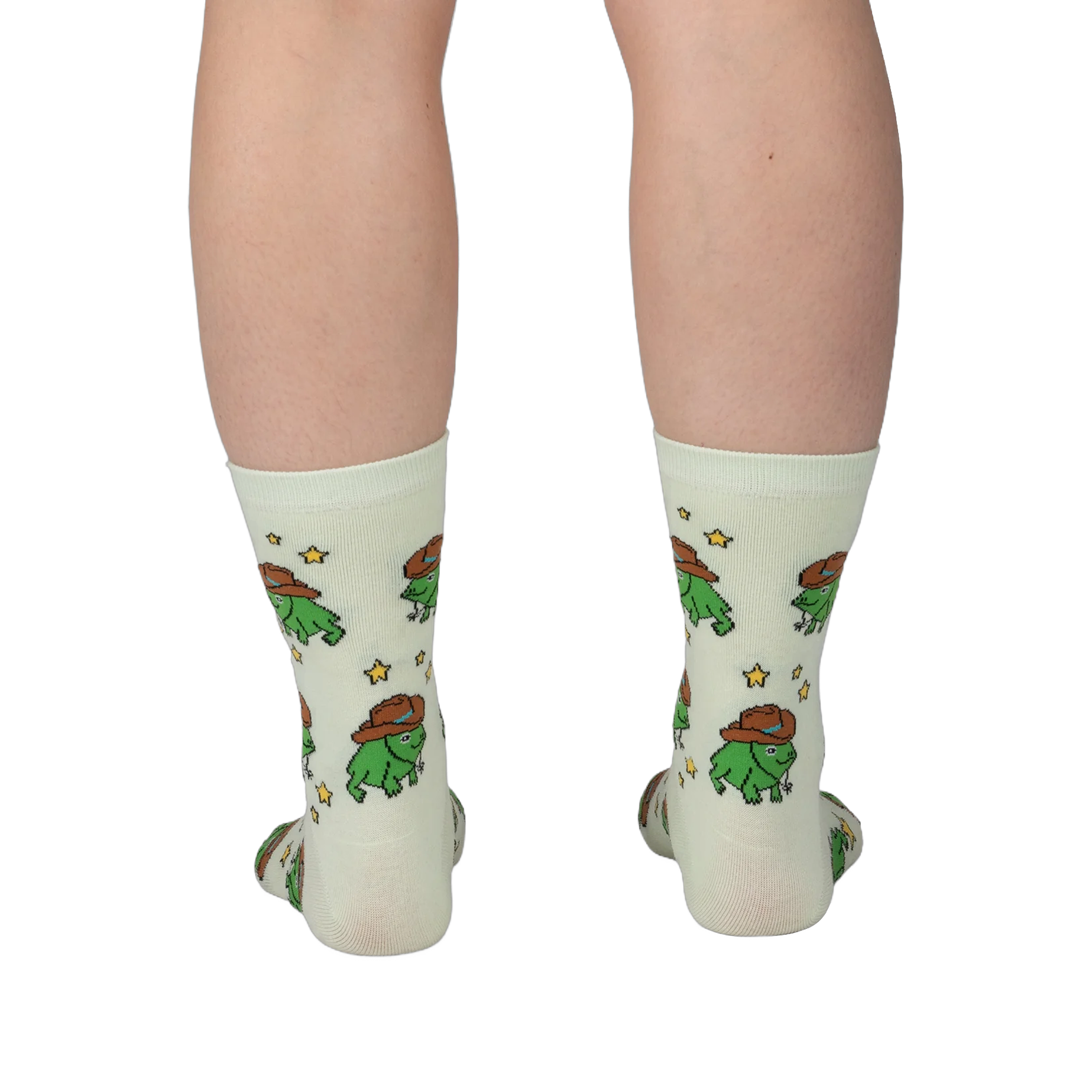 Back view of legs wearing pale crew socks featuring a pattern of green pixel frogs in brown cowboy hats and yellow stars.