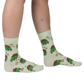 Person wearing pale mint crew socks featuring a repeating pattern of green pixel-art frogs in brown cowboy hats and stars.