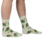Person wearing pale mint crew socks featuring a repeating pattern of green pixel-art frogs in brown cowboy hats and stars.