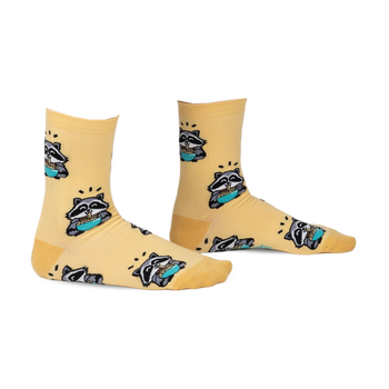 Pair of pastel yellow crew socks featuring a repeating pattern of raccoons enjoying ramen. 