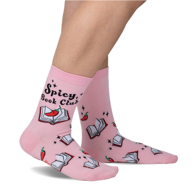 A person stands wearing light pink crew socks featuring open books with red chili peppers and "Spicy, Book Club" text.