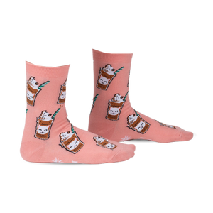 Pair of peach-colored crew socks with a repeating pattern of cartoon cats in coffee cups.  Features green straws and coffee bean accents.