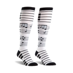 Pair of black and white knee-high socks.  The socks have a musical staff and notes design.