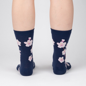 Back view of a person wearing navy blue crew socks with a pink cherry blossom pattern.