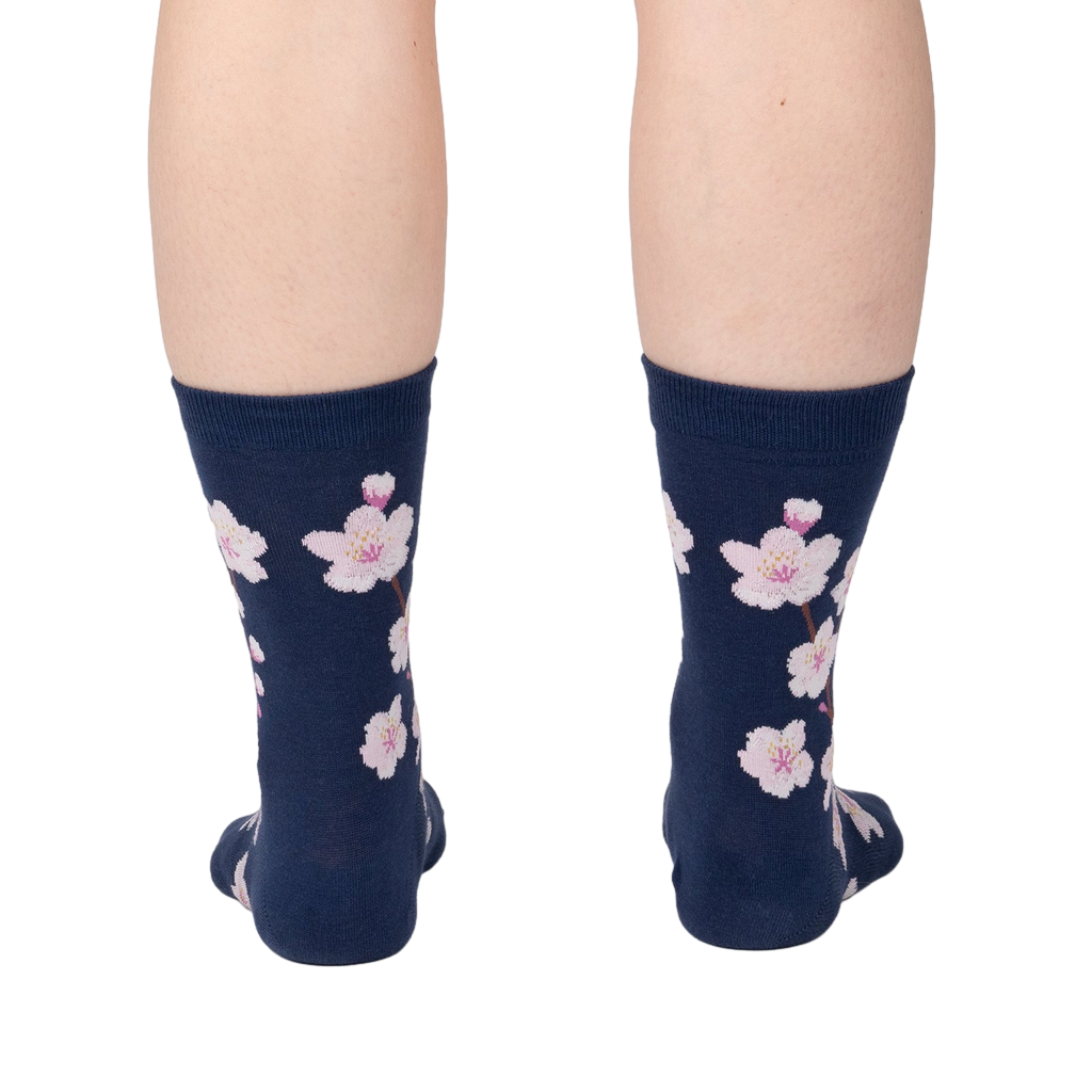 Back view of a person wearing navy blue crew socks with a pink cherry blossom pattern.