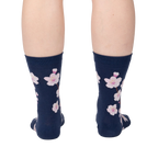 Back view of a person wearing navy blue crew socks with a pink cherry blossom pattern.