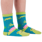 A person's legs and feet wearing the fuzzy teal blue slipper socks, shown from the side.