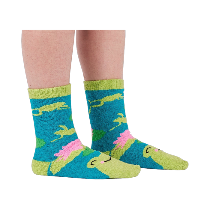 A person's legs and feet wearing the fuzzy teal blue slipper socks, shown from the side.