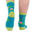 A person's legs and feet, viewed from behind, wearing the fuzzy teal blue slipper socks with visible grippers on the soles.