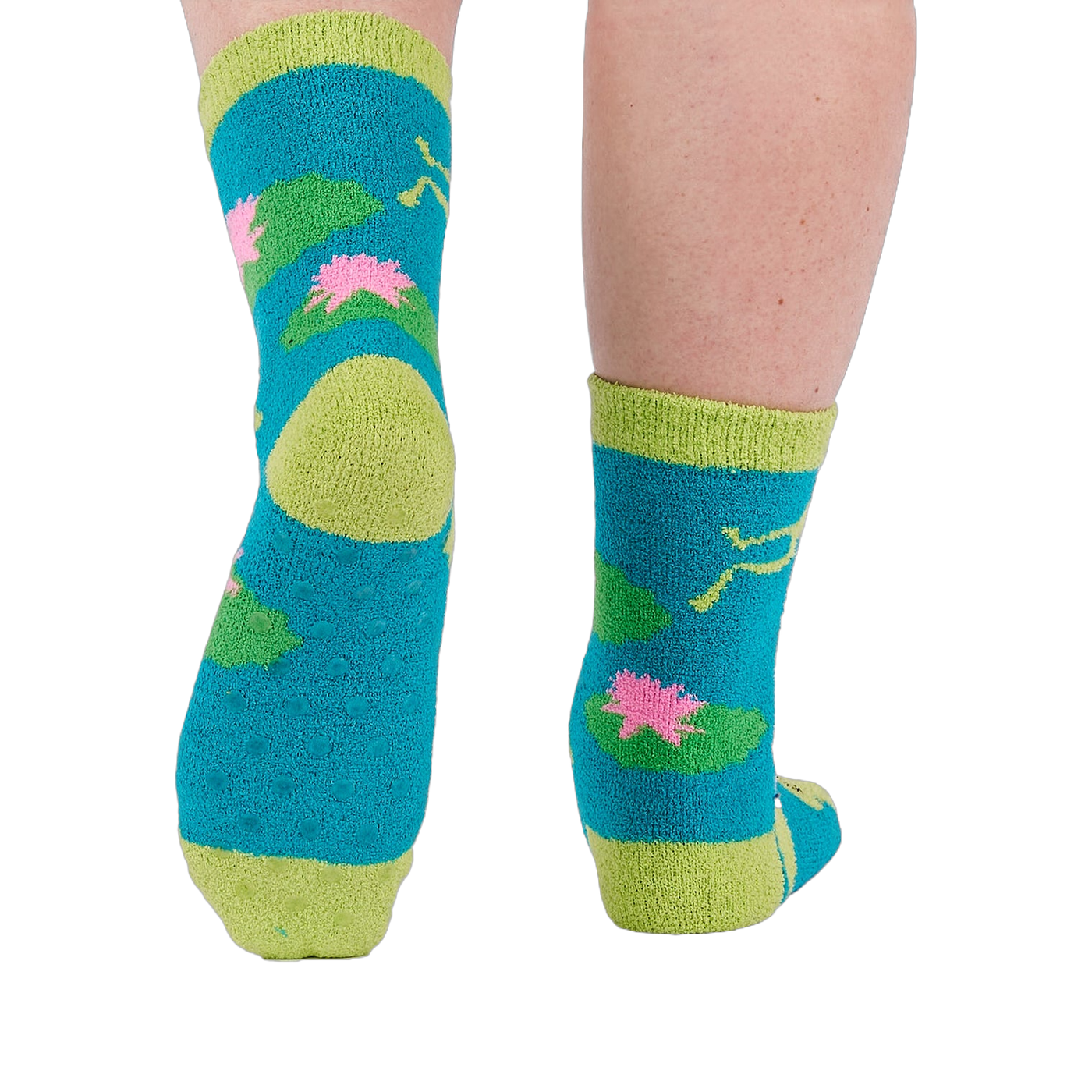 A person's legs and feet, viewed from behind, wearing the fuzzy teal blue slipper socks with visible grippers on the soles.