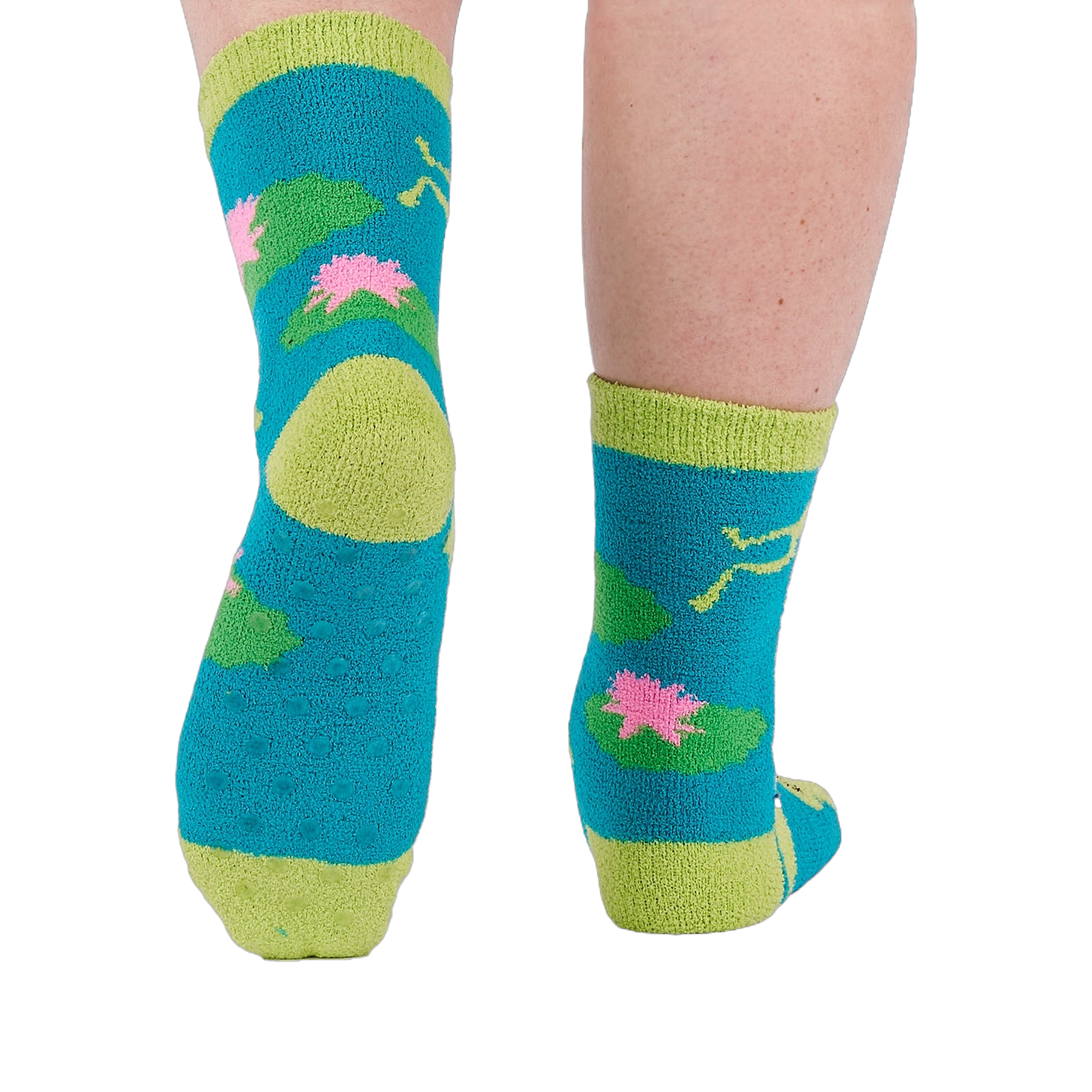 A person's legs and feet, viewed from behind, wearing the fuzzy teal blue slipper socks with visible grippers on the soles.