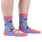 Person wearing fuzzy periwinkle slipper socks with bee, mushroom, and flower patterns, side view.