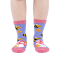 Person wearing fuzzy periwinkle slipper socks with bee, mushroom, and flower patterns, front view.