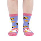Person wearing fuzzy periwinkle slipper socks with bee, mushroom, and flower patterns, front view.