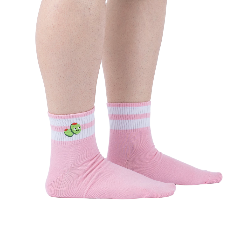 Lifestyle shot of person wearing pink ankle socks with olive embroidery and white stripes.