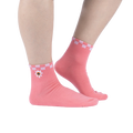 Lifestyle shot showing the socks on a person's feet. The socks are pink with a white and pink checkered cuff and embroidered daisy with an eye in the center.