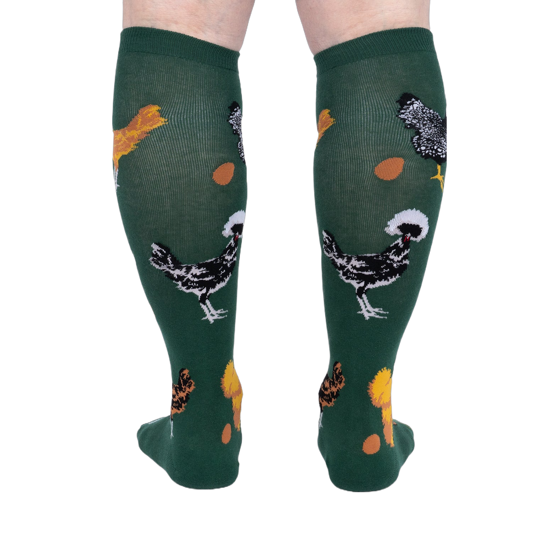 Person wearing dark green knee-high socks patterned with various chickens and eggs, standing, back view.