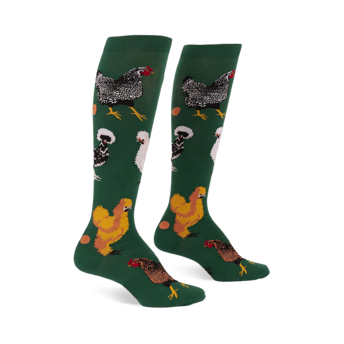Pair of knee-high dark green socks featuring various types of chickens- mottled black, fluffy white, golden brown- with scattered eggs.
