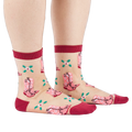 A person's legs and feet, wearing sheer pink cowboy boot socks from the side. Legs are bare against a white background.