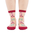 A person's legs and feet, wearing sheer pink cowboy boot socks, viewed from the front against a white background.