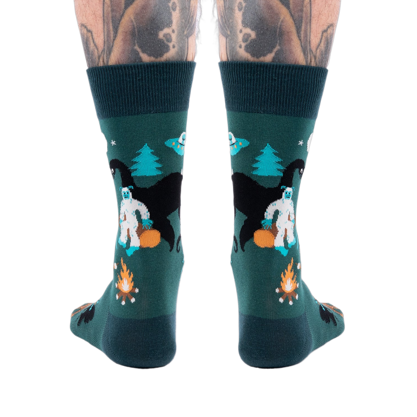 Back view of a person's lower legs with tattoos, wearing dark green cryptid socks with Yeti, Mothman, and UFO.