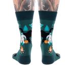 Back view of a person's lower legs with tattoos, wearing dark green cryptid socks with Yeti, Mothman, and UFO.