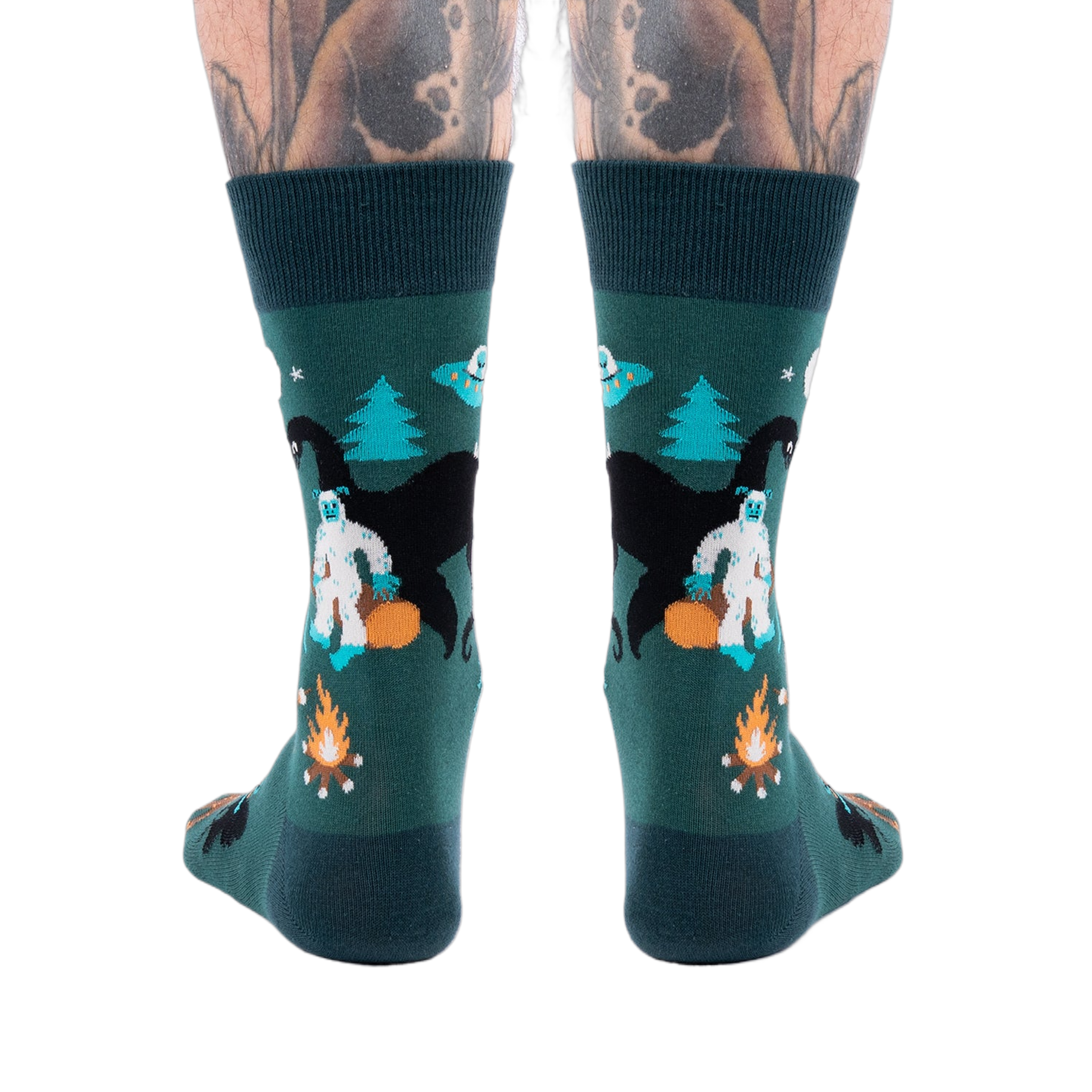 Back view of a person's lower legs with tattoos, wearing dark green cryptid socks with Yeti, Mothman, and UFO.