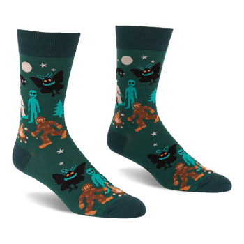 Pair of dark green crew socks with a repeating pattern of Bigfoot, Mothman, alien, Yeti, campfire, trees, moon, and stars.