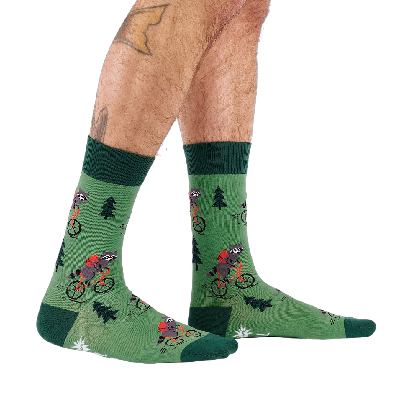 Person's lower legs and feet, seen from the side, wearing green raccoon bicycle socks. White background.
