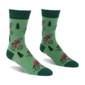 Pair of green socks with raccoons on red bicycles, wearing red backpacks, among dark green pine trees. Darker green cuffs, heels, toes.