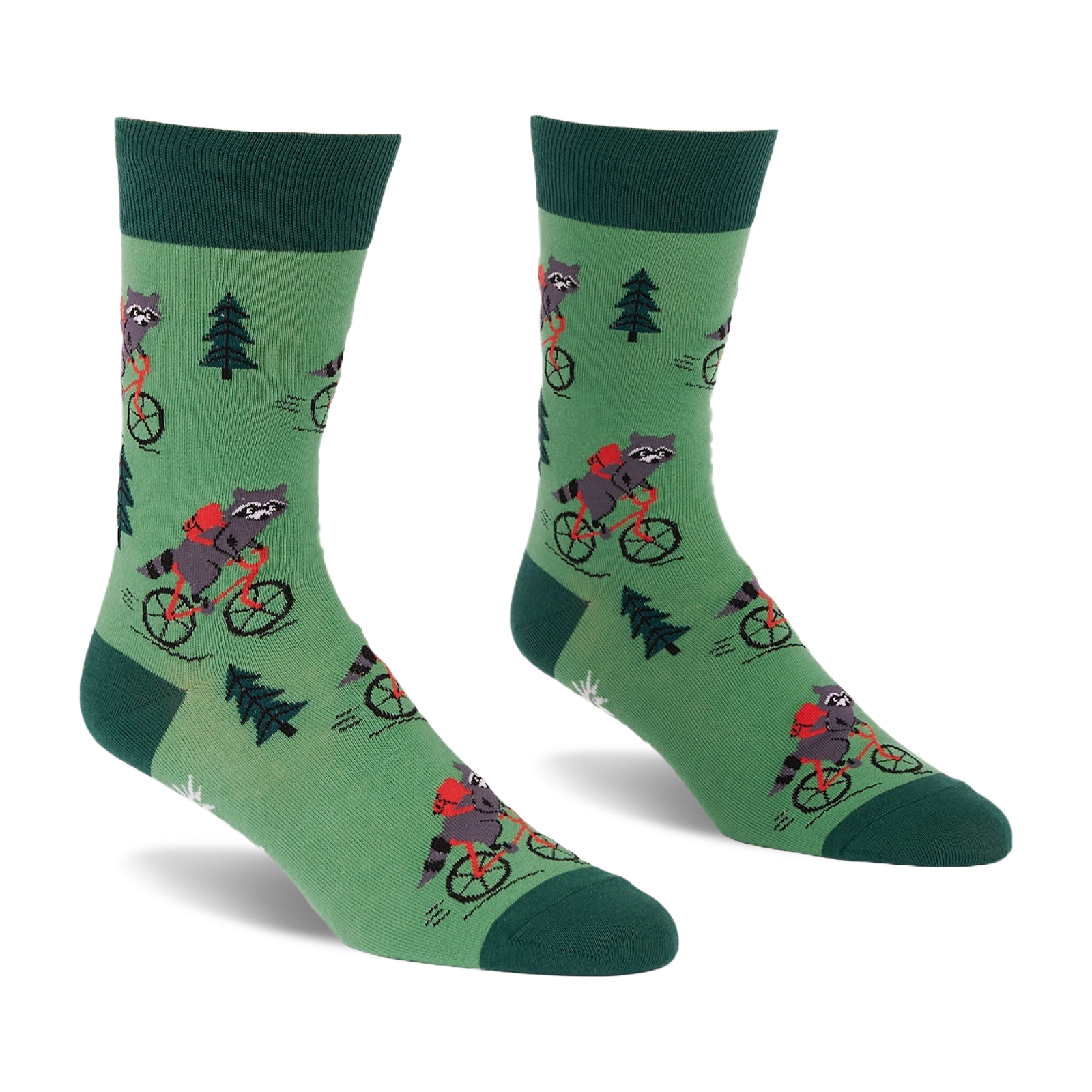 Pair of green socks with raccoons on red bicycles, wearing red backpacks, among dark green pine trees. Darker green cuffs, heels, toes.