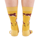 Person standing, wearing mustard yellow crew socks with flying squirrel pattern, viewed from the back.