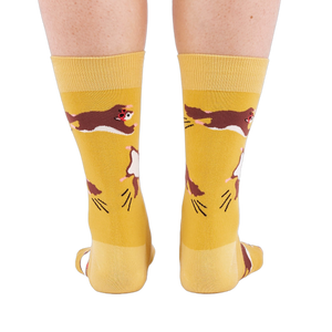 Person standing, wearing mustard yellow crew socks with flying squirrel pattern, viewed from the back.