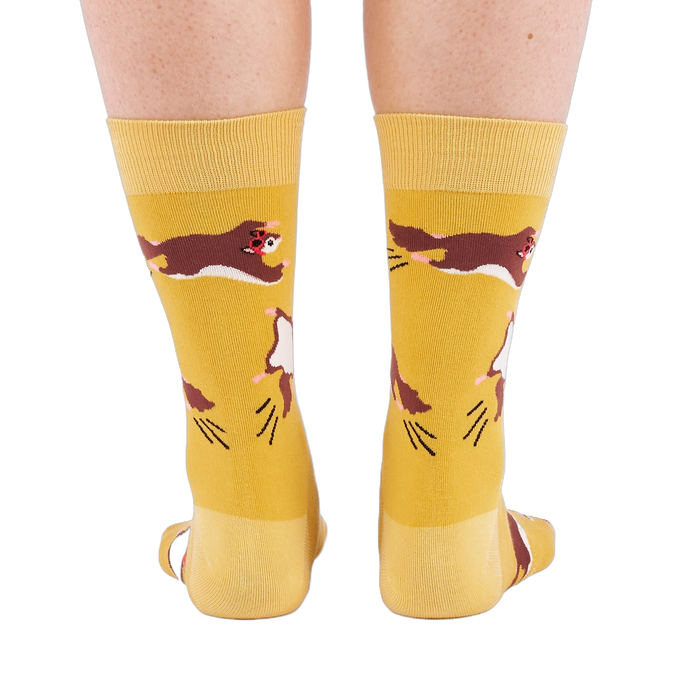 Person standing, wearing mustard yellow crew socks with flying squirrel pattern, viewed from the back.