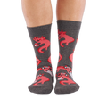 Full-length shot of a person's legs, viewed from the front, wearing grey axolotl gaming crew socks on a white background.