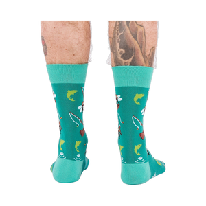 Back view of a person wearing teal fly fishing socks, showing leg hair and tattoos on both calves.