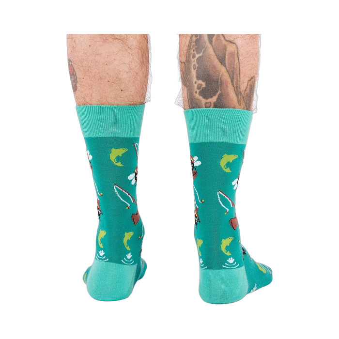 Back view of a person wearing teal fly fishing socks, showing leg hair and tattoos on both calves.