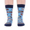 Person standing forward wearing light blue crew socks with fish and knot patterns on a white background.
